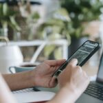 Unrecognizable person browsing smartphone in room with houseplants