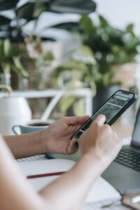 Unrecognizable person browsing smartphone in room with houseplants